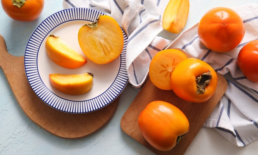 Wooden,Board,And,Plate,With,Sweet,Ripe,Persimmons,On,White